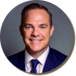 Professional man in a suit smiling against a gray background.