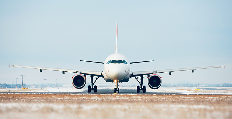 Airplane on runway during daytime, ready for takeoff with clear skies in the background.