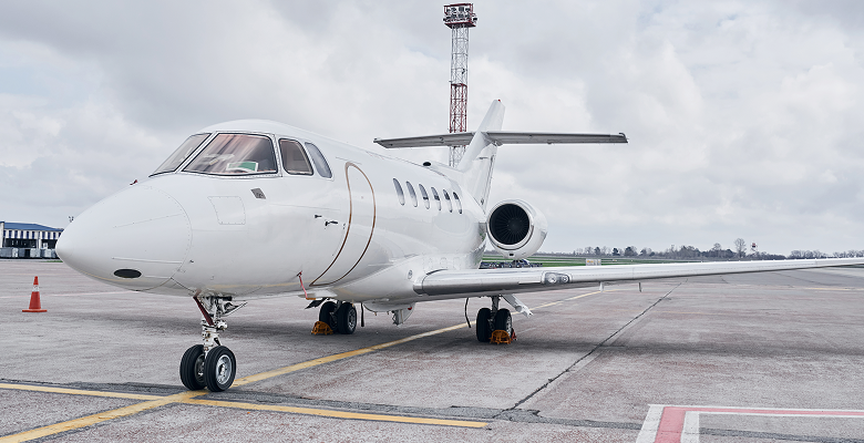 Private jet on tarmac with cloudy sky, ready for takeoff. Luxury travel and aviation concept.