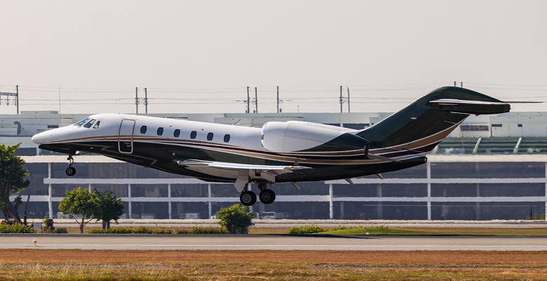Private jet landing on a runway with a clear blue sky background, showcasing luxury travel and aviation.