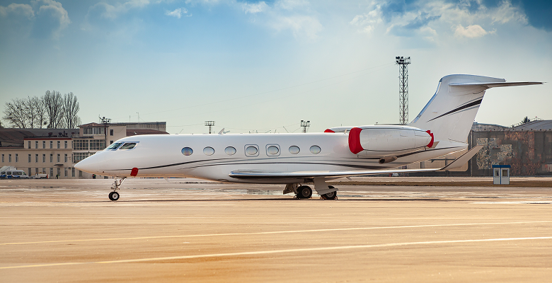 Sleek private jet parked on airport tarmac under a clear blue sky, highlighting luxury air travel.